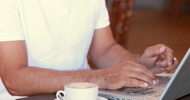 Man Typing on Laptop While Drinking Latte in Coffee Shop - Download Free Stock Images Pikwizard.com