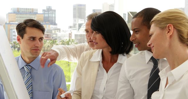 Business professionals collaborating on a presentation in a modern office with an urban backdrop in the background. Great for themes related to teamwork, business meetings, corporate settings, and workplace diversity.