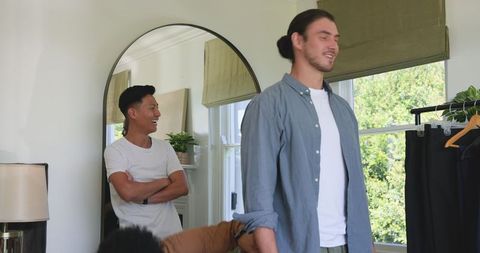 Friends helping groom getting ready in cozy bedroom