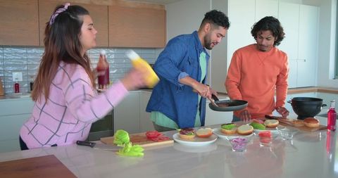 Friends preparing burgers at modern kitchen island, casual cooking and mealtime fun