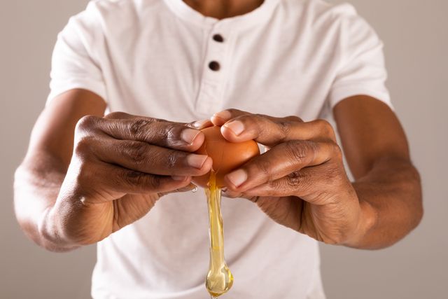 Midsection of afrcan american man breaking brown egg. unaltered, food, healthy eating, studio shot and preparation concept.