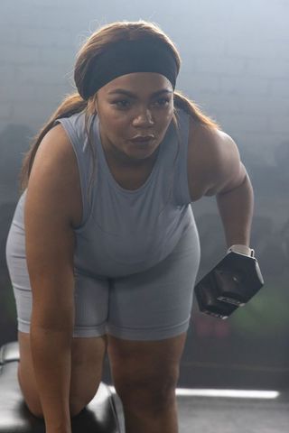 African american woman performing hex dumbbell single-arm row on bench showing strength