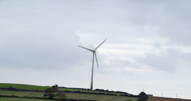 Wind Turbine on Rolling Hills Under Cloudy Sky - Download Free Stock Images Pikwizard.com