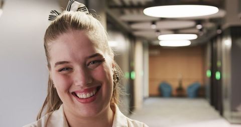 Confident Woman Smiling in Modern Office Corridor Interior