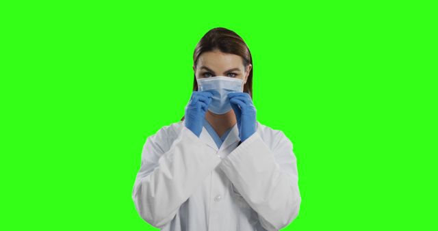 Female Doctor Adjusting Face Mask Wearing White Lab Coat Against Green Background - Download Free Stock Images Pikwizard.com