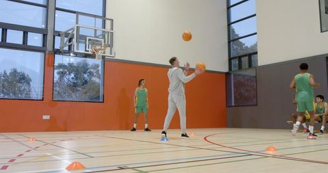 Basketball coach juggling balls with players in training session