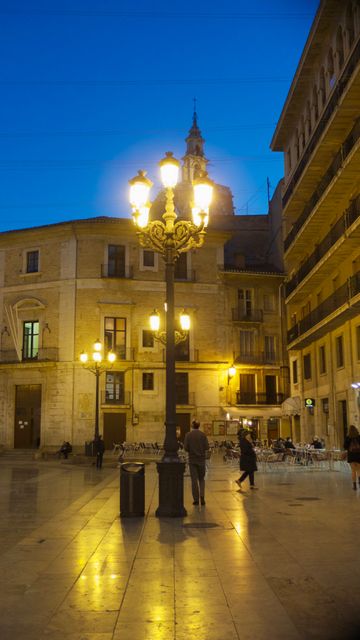 Scene captures serene evening in a historic European town square. Gentle twilight illuminates architecture, traditional street lamps casting warm glow on cobblestone streets. Suitable for depicting travel destinations, romantic getaways, or urban exploration.