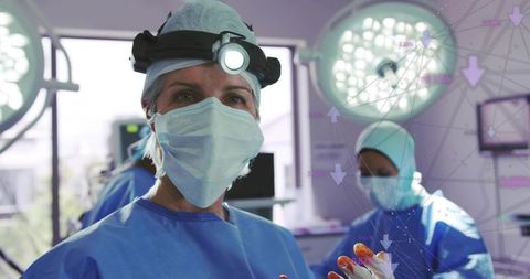 Lead surgeon performing surgery with headlamp and bloodied gloves, surgical team