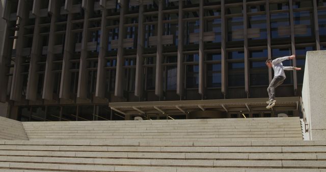 Young man skateboarding down city stairs outside modern building - Download Free Stock Images Pikwizard.com