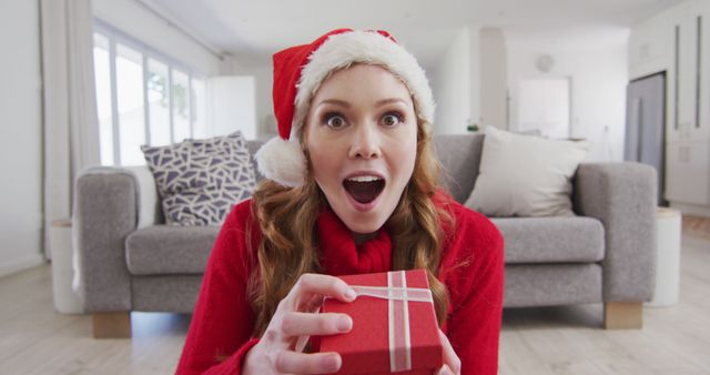 Excited Woman Wearing Santa Hat Holding Christmas Gift - Download Free Stock Images Pikwizard.com