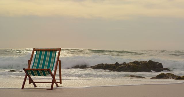 Front view of a green and brown wooden sun lounger on the beach with waves at the back