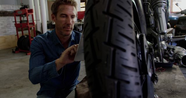 Man Working on Motorcycle Wheel in Garage Workshop - Download Free Stock Images Pikwizard.com