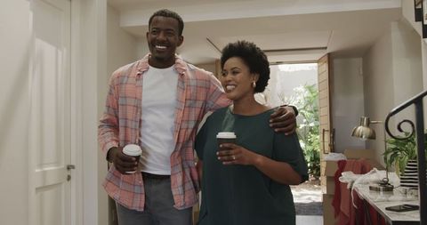 Smiling friends enjoying coffee indoors, embraced in warm friendship