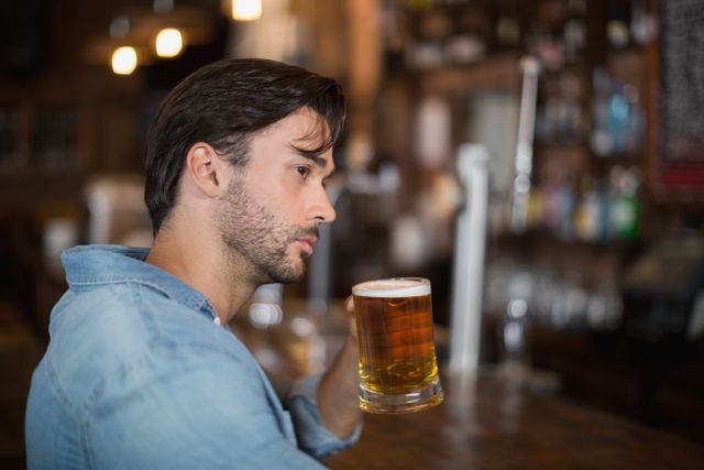 Thoughtful man looking away while drink beer at pub