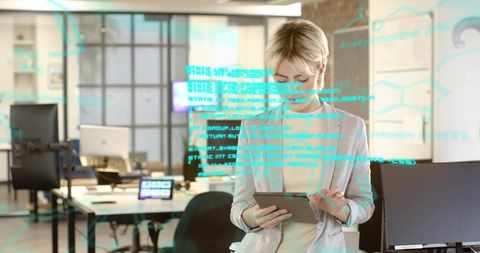 Midcareer woman working on tablet scanning code overlay in modern open office tech hub