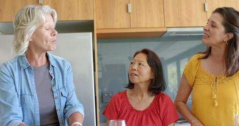 Multigenerational women chatting in bright kitchen, diverse friends sharing conversation