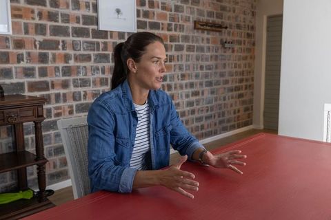 Woman engaged in discussion at red tabletop in brick wall interior