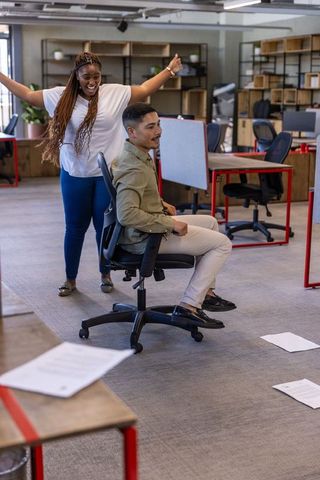 Coworkers enjoying team bonding with office chair fun