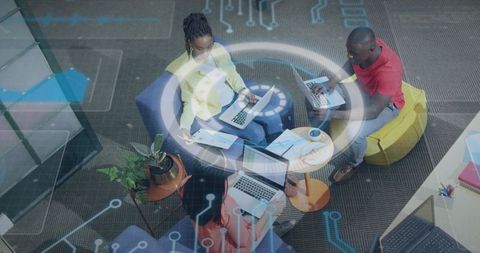 Diverse team collaborating around lounge table using laptops with futuristic hud overlay