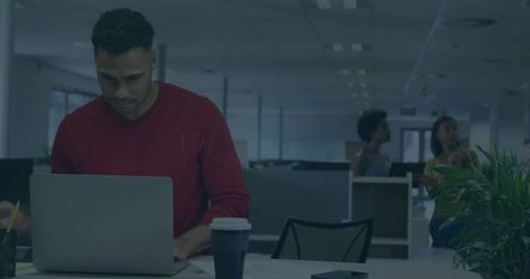 Focused Young Professional Typing on Laptop in Modern Open-Plan Office