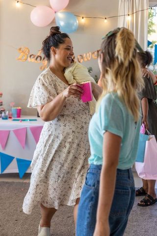 Joyful female friends celebrating baby shower with presents