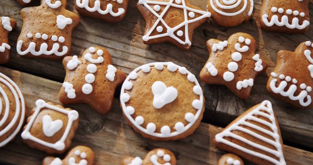A variety of gingerbread cookies with white icing designs are spread out on a wooden surface, showcasing a festive and creative array of patterns. These homemade treats add a touch of warmth and tradition to holiday celebrations.