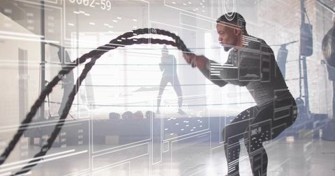 Male athlete swinging battle ropes during high-intensity gym training with hud overlay