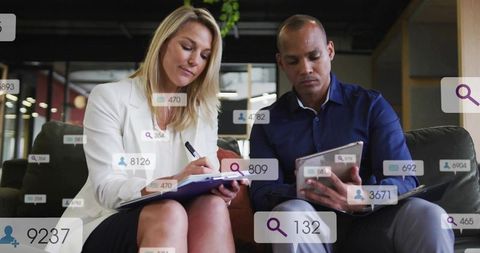 Business team collaborating in office lounge using tablet and notebook with data overlays