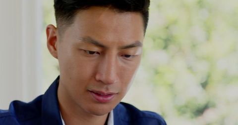 Asian Man Concentrating During Phone Call in Park Environment