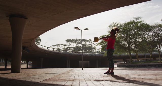 Woman exercising with kettlebell outdoors under highway - Download Free Stock Images Pikwizard.com