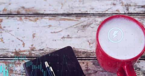 Red ceramic mug with frothy drink and lightning icon overhead rustic wood flatlay