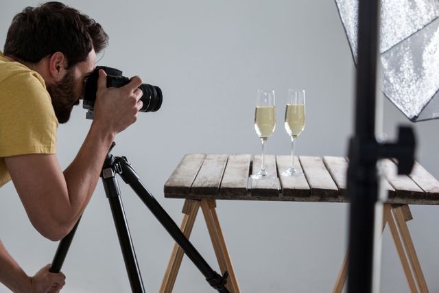 Male photographer photographing champagne glasses in studio