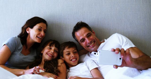 Happy family relaxing on bed and taking selfie together - Download Free Stock Images Pikwizard.com