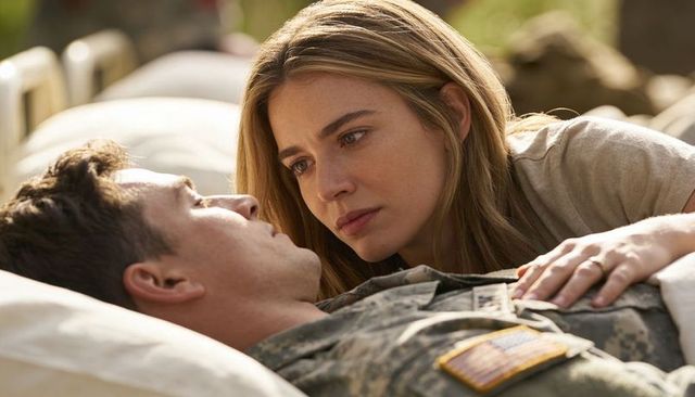 Leaning woman comforting soldier on cot in military field camp