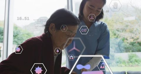 Caregiver guiding elderly woman using tablet with holographic health interface at home