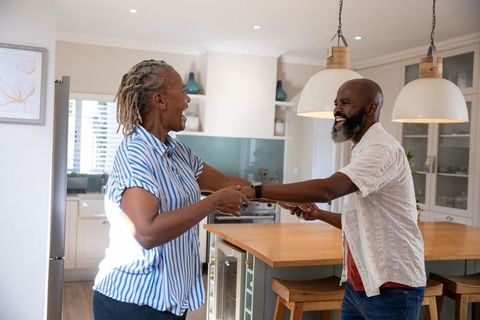 Senior african american couple dancing cheerfully in modern kitchen