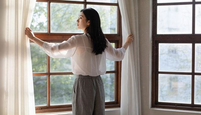 Opening Curtains at Morning Window, Contemplative Woman Embracing Soft Daylight