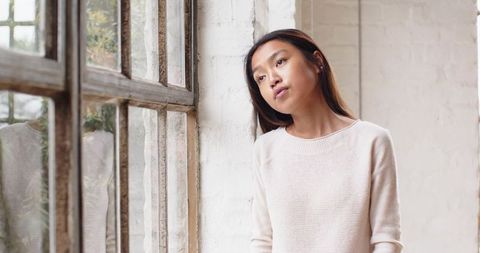 Pensive woman leaning against brick wall in urban loft