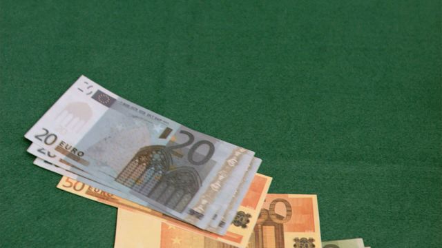 European currency banknotes in slow motion on green felt poker table. Suitable for use in content related to gambling, finance, casinos, and money management.