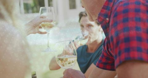 Friends toasting white wine poolside during casual summer patio gathering