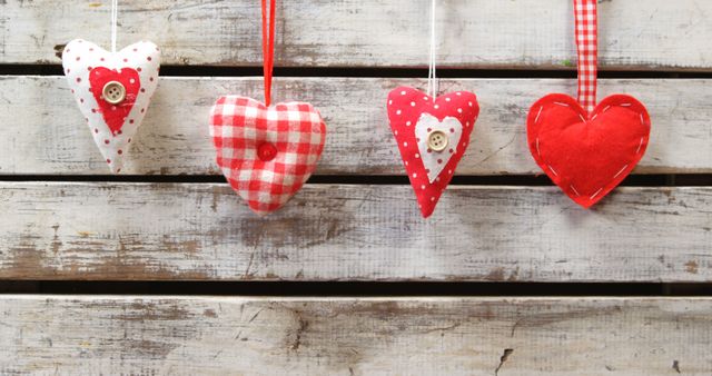 Handmade fabric hearts hang against a rustic wooden background, symbolizing love and the art of crafting. These charming decorations evoke a sense of warmth and nostalgia, perfect for festive occasions or as home decor.