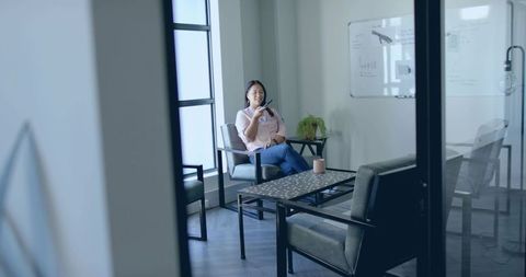 Businesswoman Speaking into Smartphone in Modern Office Lounge