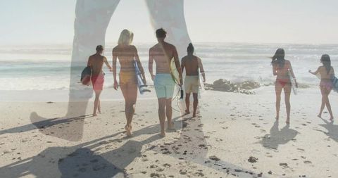 Group of friends carrying surfboards walking along beach
