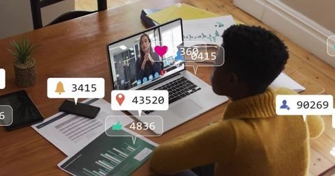 Woman in mustard sweater reviewing charts on laptop during remote video call, analyzing data