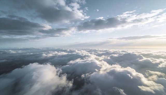 Sunlit Sea of Cumulus Clouds Drifting Toward Distant Horizon at High Altitude
