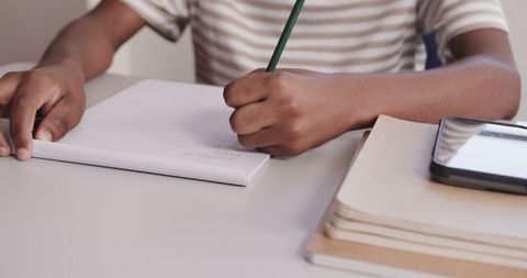 Child Writing in Notebook at Home Study Desk