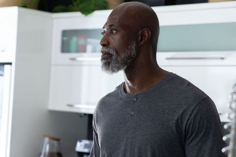 Mature african man standing and looking in modern kitchen with gray henley, contemplative pose