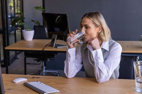 Professional in Modern Office Sipping Water for Wellness and Productivity