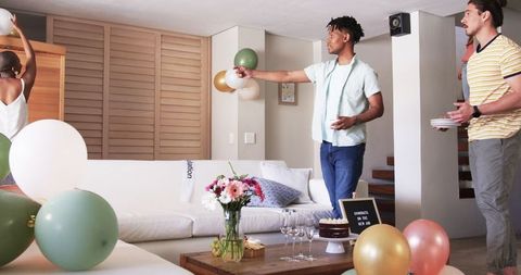 Friends Preparing Living Room for Celebration with Cake and Balloons