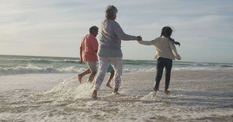 Happy Multigenerational Family Running on Beach at Sunset